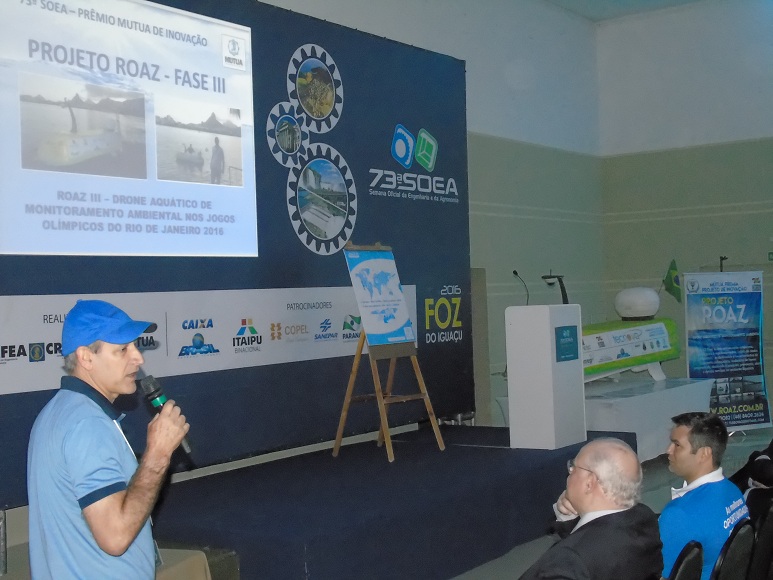 Roberto Böell apresenta seu projeto de "drone aquático". À direita a embarcação que está em exposição na Soea